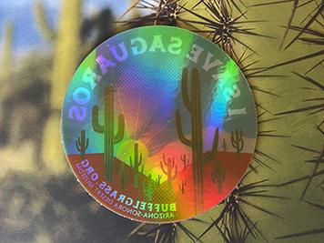 Holographic I Save Saguaros sticker in front of a saguaro