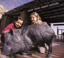 Two young girls playing with the bronze javalinas on the front patio 